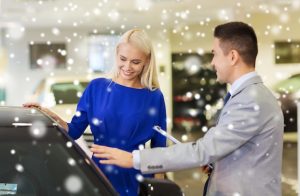 Uma Mulher Feliz Está Ao Lado De Um Revendedor De Carros Em Um Salão Do Automóvel, Rodeada Por Um Efeito De Neve, Destacando Uma Venda De Carros E O Consumismo.