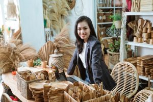 Uma Mulher Asiática Atraente Está Em Sua Loja De Artesanato, Exibindo Produtos Feitos à Mão A Partir De Materiais Naturais, Incorporando O Espírito Empreendedor.