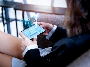 Uma Empresária Analisando Um Gráfico De Investimento Digital Na Tela De Um Smartphone, Representando Conceitos De Crescimento Financeiro E Tecnologia Na Indústria Sextech.